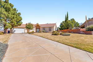 View of front facade with a front yard, a garage, concrete driveway, and stucco siding