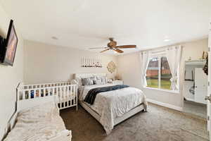 Carpeted bedroom featuring a ceiling fan and baseboards