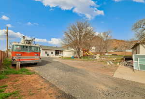 View of front of home featuring a playground, gravel driveway, an outbuilding, and a garage