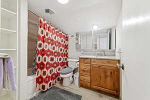 Full bath with vanity, light wood finished floors, and shower / bath combo with shower curtain