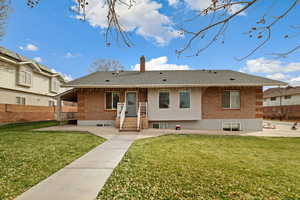 View of front of house featuring brick siding, a front lawn, a chimney, and a shingled roof