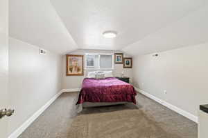 Bedroom with a textured ceiling and light colored carpet