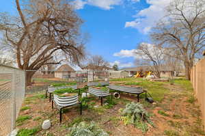Fenced backyard with a residential view and a vegetable garden