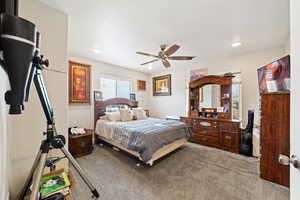 Carpeted bedroom with ceiling fan and recessed lighting