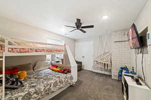 Bedroom with dark colored carpet, ceiling fan, and a textured ceiling