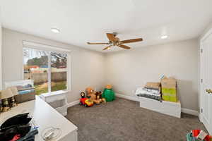 Recreation room featuring dark colored carpet and ceiling fan