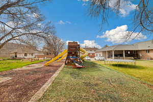 View of play area with a trampoline, a patio, and a yard