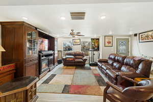 Living room with ceiling fan, light wood-style floors, and recessed lighting