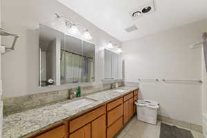 Bathroom featuring double vanity, a shower with curtain, and light tile patterned flooring