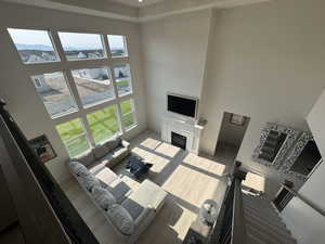 Living area with a glass covered fireplace, a high ceiling, light wood-style flooring, healthy amount of natural light, and a residential view