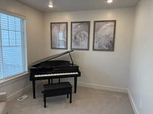 Living area with light carpet and recessed lighting