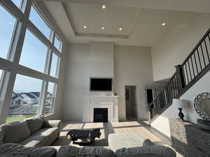 Living room featuring a tiled fireplace, recessed lighting, wood finished floors, and a raised ceiling