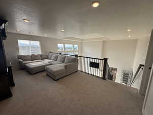 Living area with a textured ceiling, recessed lighting, carpet flooring, plenty of natural light, and a tray ceiling