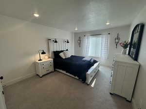 Bedroom with light colored carpet, a textured ceiling, and recessed lighting