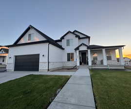 View of front of home featuring stone siding, a yard, a porch, and driveway
