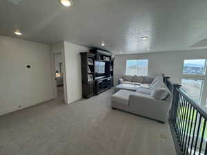 Living room with a textured ceiling, light colored carpet, and recessed lighting
