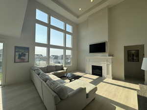 Living room with light wood-style floors, a fireplace, a high ceiling, recessed lighting, and a residential view
