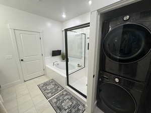 Full bathroom with a stall shower, a garden tub, and stacked washer / drying machine
