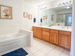 Full bathroom with double vanity, a garden tub, light tile patterned flooring, and a shower stall