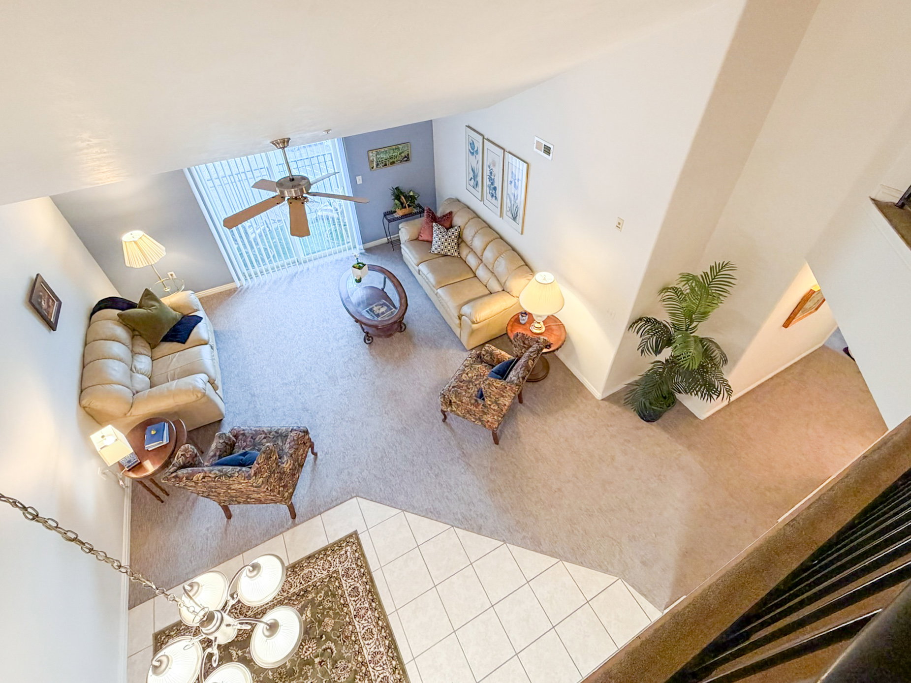 Living area with carpet floors, ceiling fan, tile patterned flooring, and a high ceiling