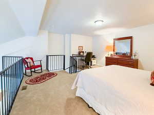 Bedroom featuring light carpet and vaulted ceiling