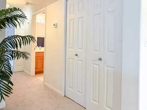 Corridor featuring light colored carpet and baseboards