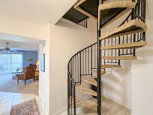 Stairs with tile patterned flooring and ceiling fan