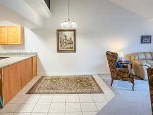 Dining area featuring hanging lights, vaulted ceiling, and light tile patterned floors