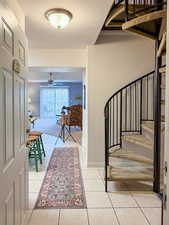Staircase featuring tile patterned floors, a ceiling fan, and carpet flooring