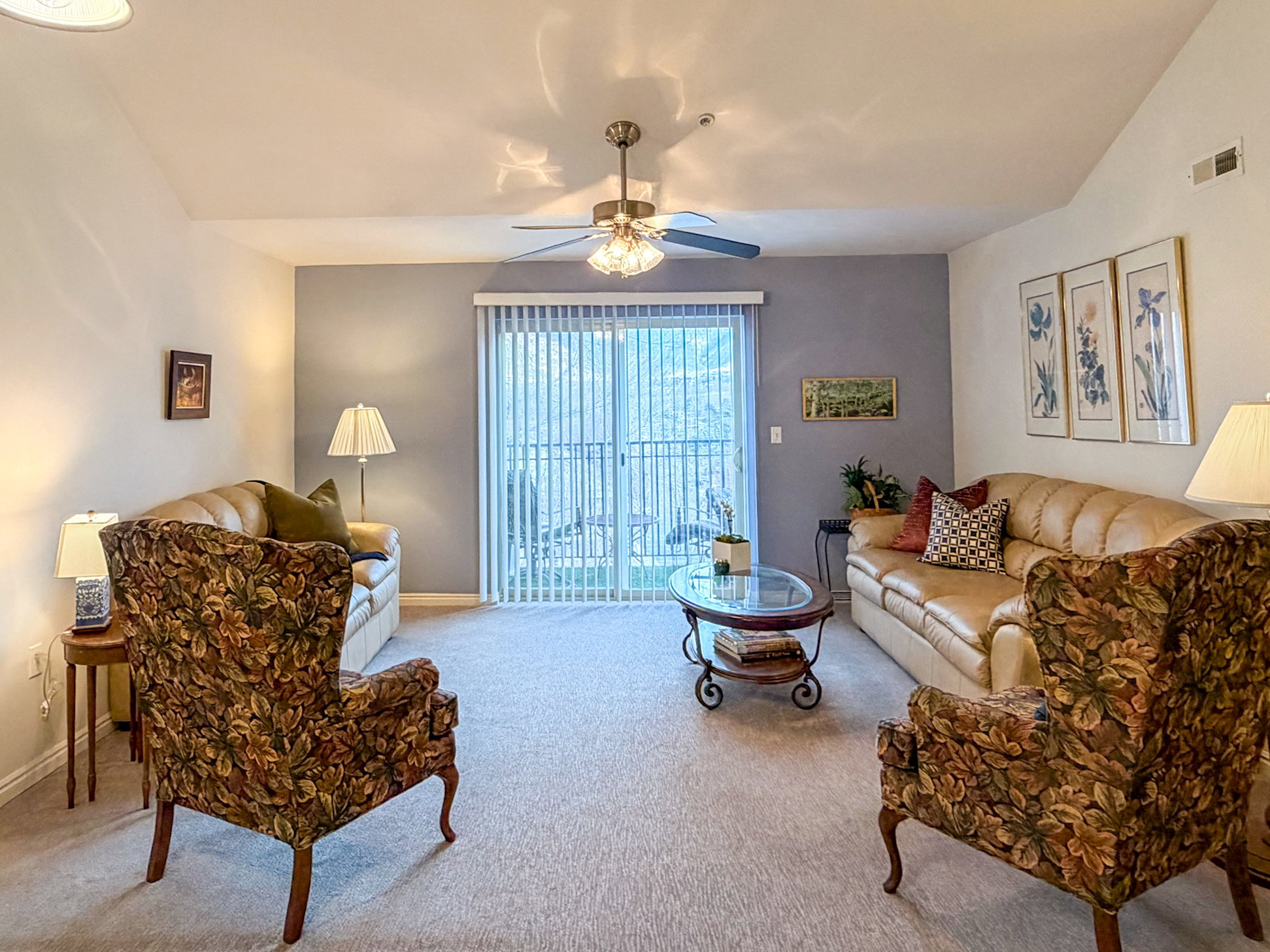 Carpeted living area with a ceiling fan and lofted ceiling