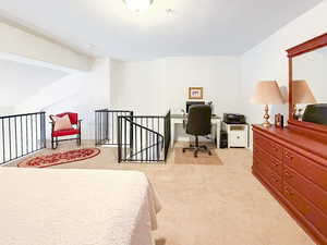 Bedroom featuring light carpet, an office area, and lofted ceiling
