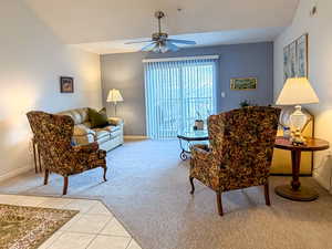 Living room with light carpet, light tile patterned floors, a ceiling fan, and vaulted ceiling