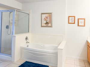 Full bath with vanity, a stall shower, light tile patterned flooring, and a bath