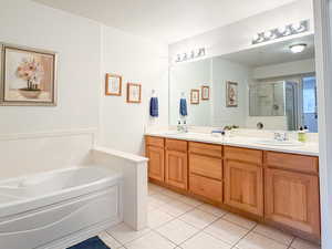 Bathroom with double vanity, a garden tub, a shower stall, and light tile patterned floors