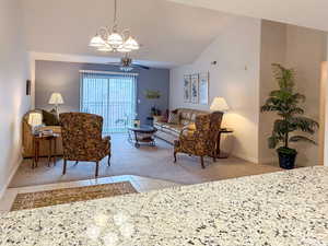 Living area with vaulted ceiling, a ceiling fan, suspended lighting, and light tile patterned floors