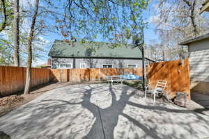 Rear view of property featuring a fenced backyard, a patio, and a shingled roof