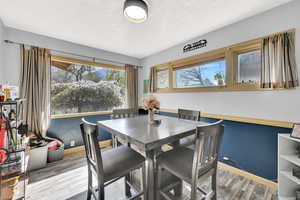 Dining space featuring wood finished floors, healthy amount of natural light, and a textured ceiling