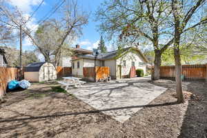 Back of property with a fenced backyard, a shed, and a chimney