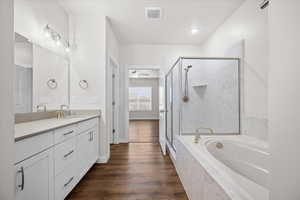 Full bathroom with vanity, a marble finish shower, a garden tub, and dark wood-style floors