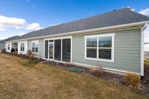 Rear view of property with a lawn, roof with shingles, a sunroom, and oil tank