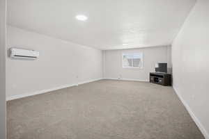 Unfurnished living room featuring light colored carpet and a wall mounted mini split