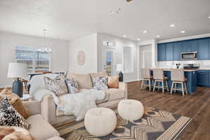 Living area featuring dark wood-style floors, a chandelier, and a ceiling fan