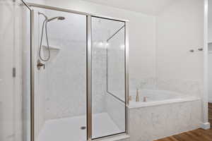 Bathroom with a marble finish shower, wood finished floors, and a bath