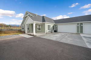 View of front of house featuring a shingled roof, a garage, driveway, and a mountain view