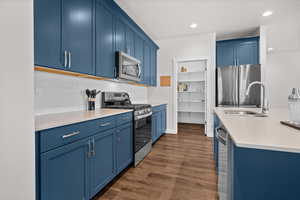 Kitchen featuring blue cabinetry, stainless steel appliances, dark wood-style floors, recessed lighting, and backsplash