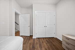 Bedroom with dark wood-style floors and a closet