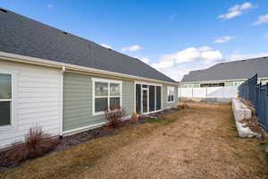 Back of property featuring a shingled roof, a sunroom, and a fenced backyard