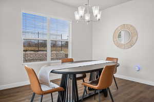 Dining room with a chandelier and dark wood-type flooring