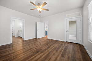 Unfurnished bedroom with dark wood-type flooring, a ceiling fan, ensuite bath, and multiple windows