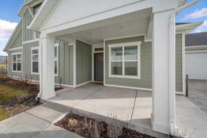Doorway to property with board and batten siding, a porch, and an attached garage